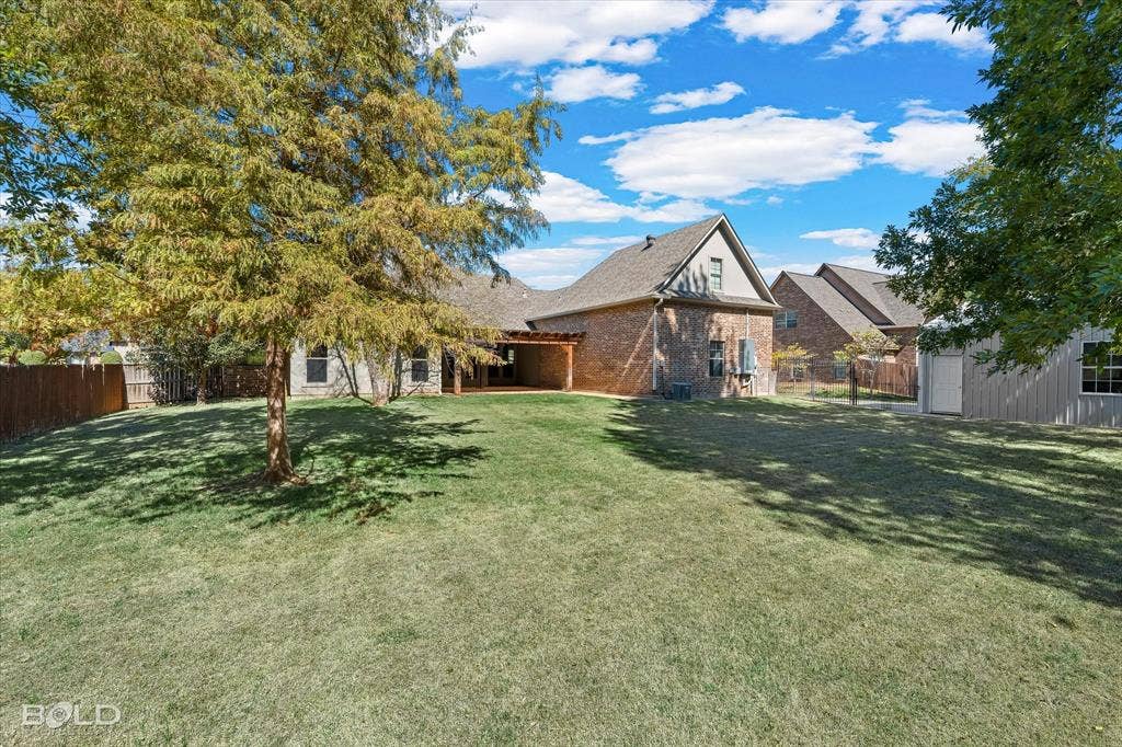 718 Duckwater Landing, Bossier City, LA 71111 Expansive backyard featuring a brick exterior, covered wood-frame patio, mature trees, and perimeter wood fencing