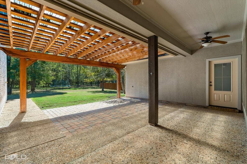 718 Duckwater Landing, Bossier City, LA 71111 Covered patio featuring a wood pergola, aggregate concrete flooring, an inlaid paver section, a ceiling fan, and a single-light exterior door