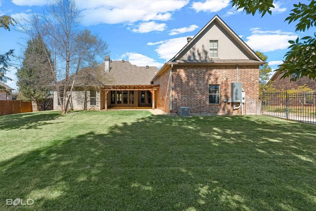 718 Duckwater Landing, Bossier City, LA 71111 Brick exterior featuring a wooden pergola, gabled roofline, and an expansive lawn