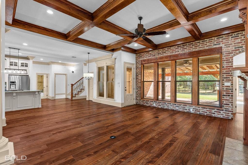 718 Duckwater Landing, Bossier City, LA 71111 Coffered wood ceiling, exposed brick accent wall, wood-finish flooring, recessed lighting, and large windows with wood framing
