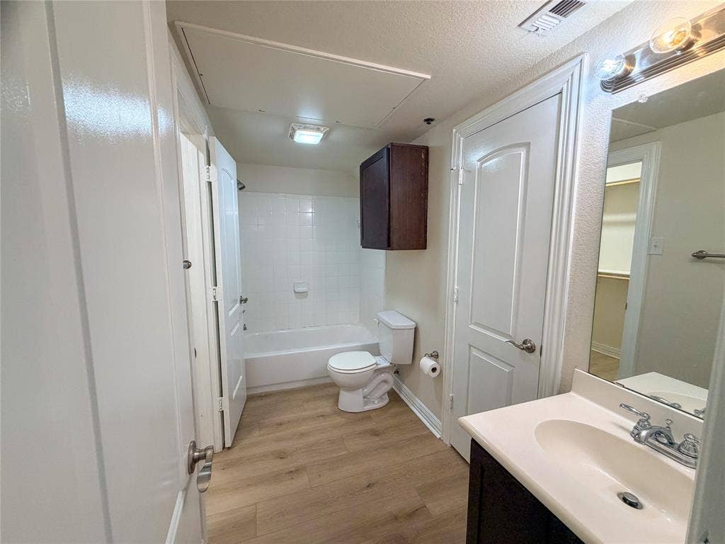 2410 S 2nd Street, #1373, Waco, TX 76706 Bathroom 2 with White bathtub with subway tile surround, wood-finish flooring, dark wood-finish vanity with white countertop, and chrome fixtures