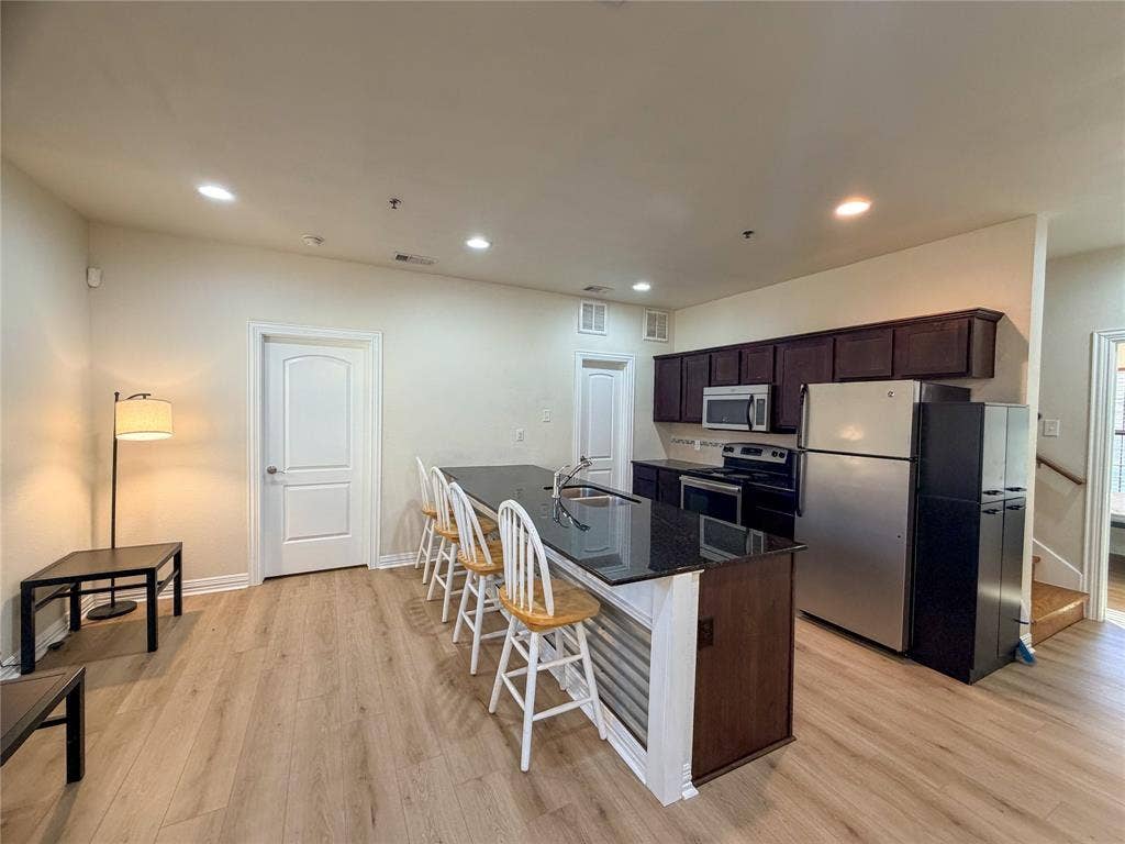 2410 S 2nd Street, #1373, Waco, TX 76706 Open-concept living area with wood-finish flooring, recessed lighting, and a kitchen island featuring a dark countertop