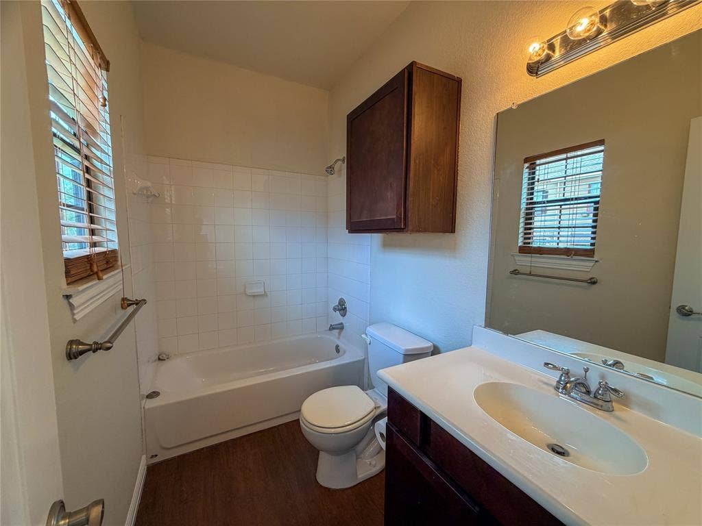 2410 S 2nd Street, #1373, Waco, TX 76706 Bathroom 3: featuring a white bathtub with tile surround, wood-finish flooring, a vanity with an integrated sink, and an overhead medicine cabinet