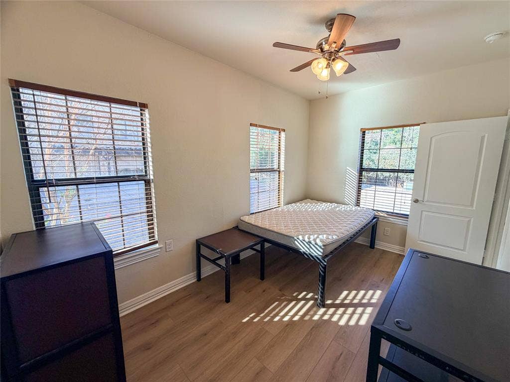 2410 S 2nd Street, #1373, Waco, TX 76706 Bedroom 1 featuring dual windows with blinds, wood-finish flooring, and a ceiling fan with integrated lighting