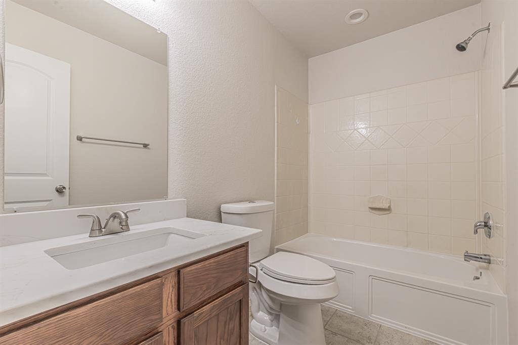 Full bathroom featuring a wood-finish vanity with an integrated sink, polished chrome faucet, and a large wall-mounted mirror