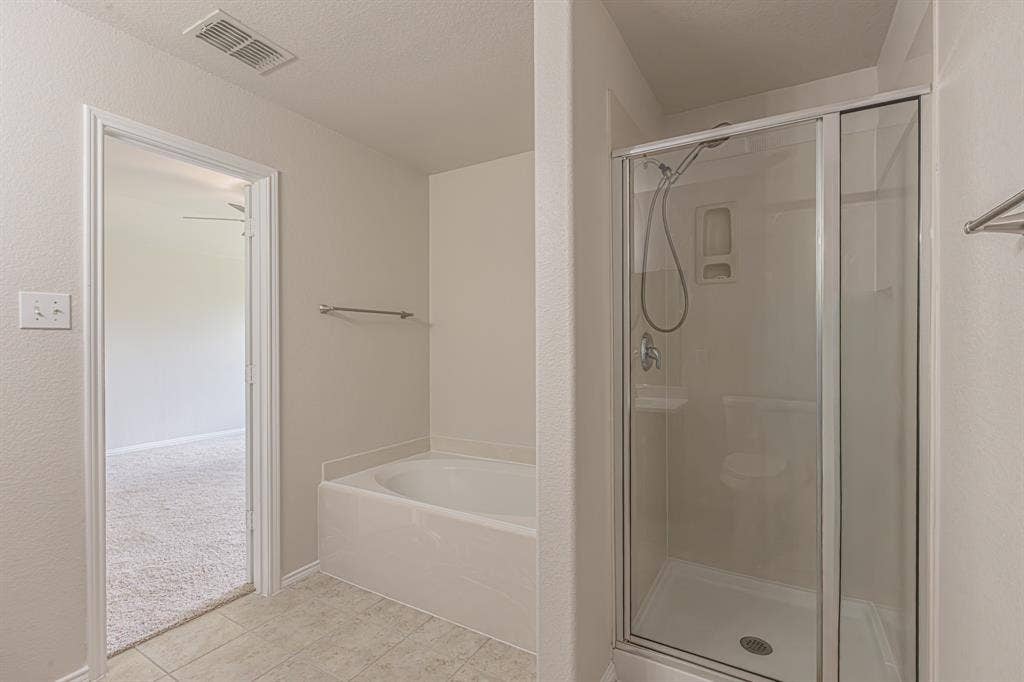 Bathroom featuring a combination shower and tub, glass-enclosed shower, built-in bathtub, tile flooring, and light-toned walls
