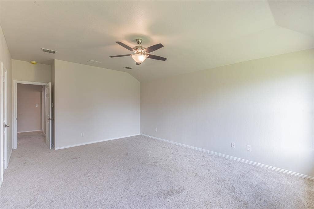 Spacious room featuring neutral carpet flooring, light-colored walls, and a ceiling fan with integrated lighting