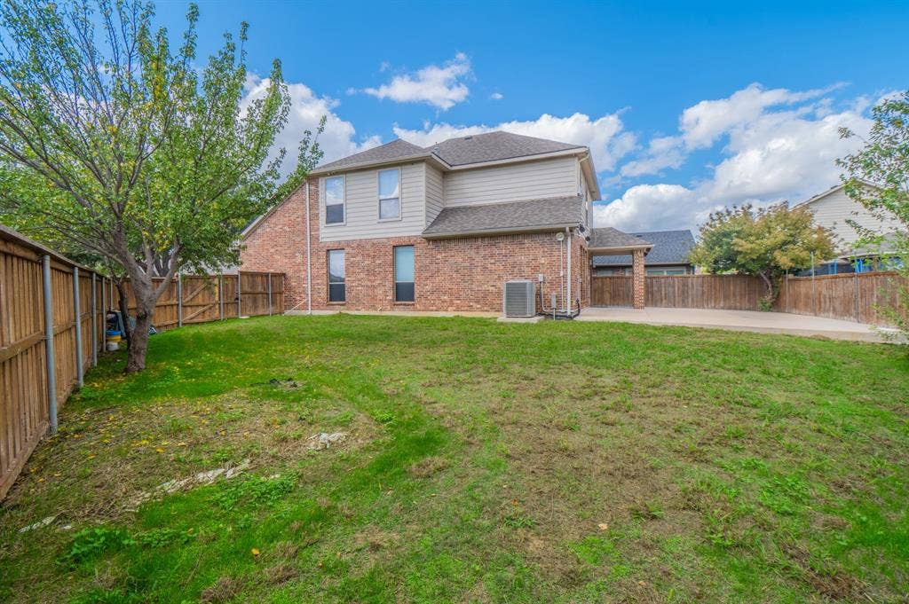 Rear exterior featuring brick and siding facade, concrete patio, and fenced yard