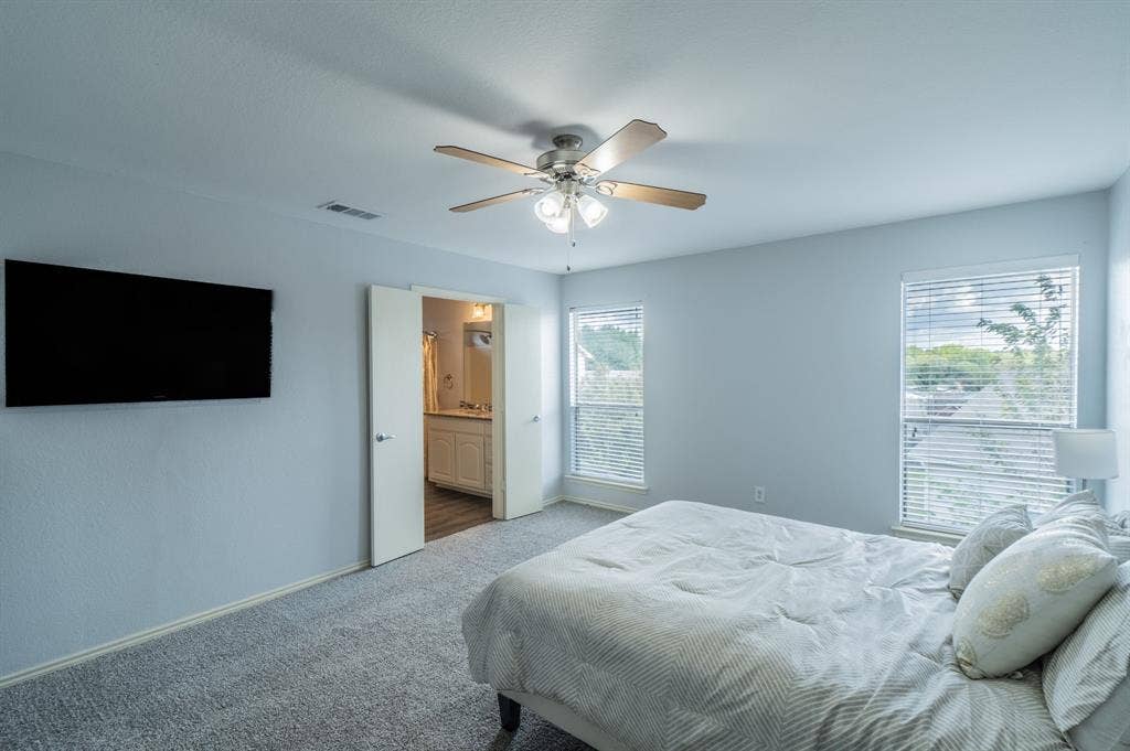 Room featuring carpeting, dual windows with horizontal blinds, and a ceiling fan with integrated light fixture