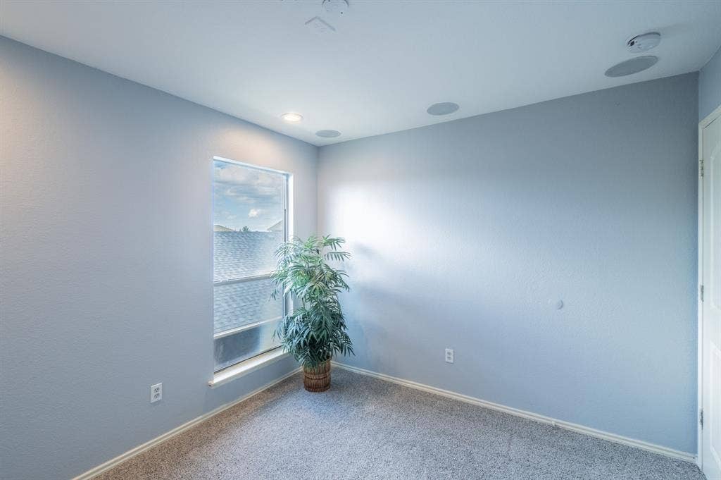 Interior room featuring neutral-toned carpeting, recessed ceiling lighting, integrated ceiling speakers, and a single-pane window