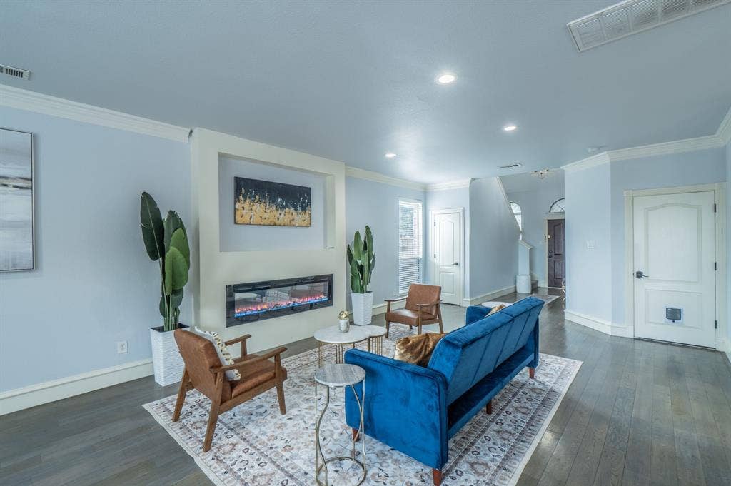 Living area featuring wood-finish flooring, recessed lighting, crown molding, and a built-in recessed fireplace with a central niche