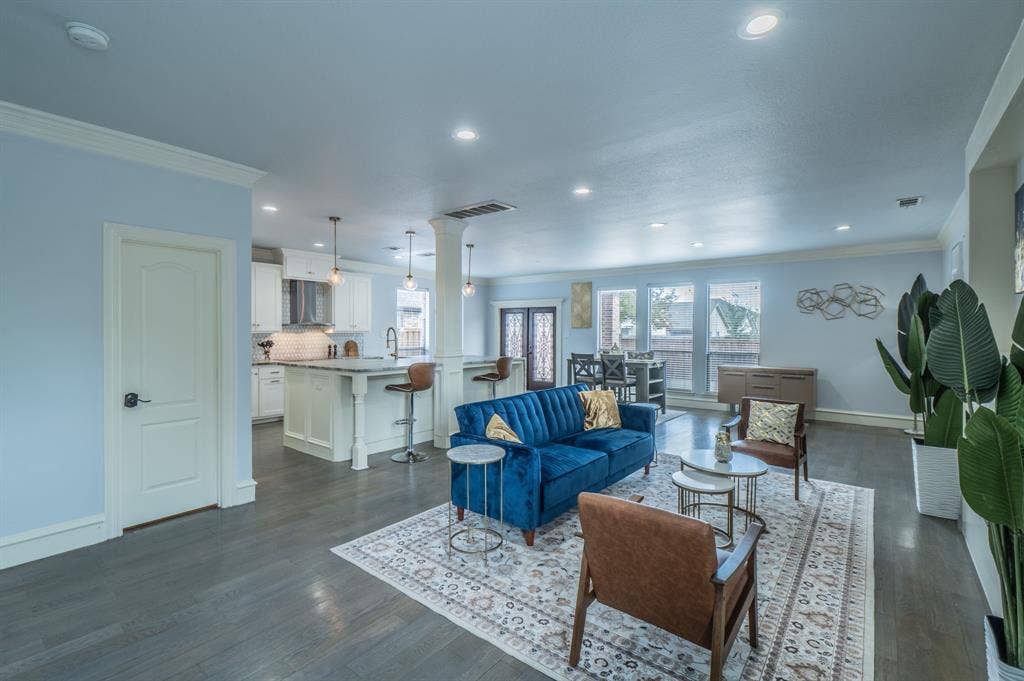 Open-concept space featuring wood-finish flooring, recessed lighting, a central structural column, and a kitchen island with stone countertops and pendant lighting
