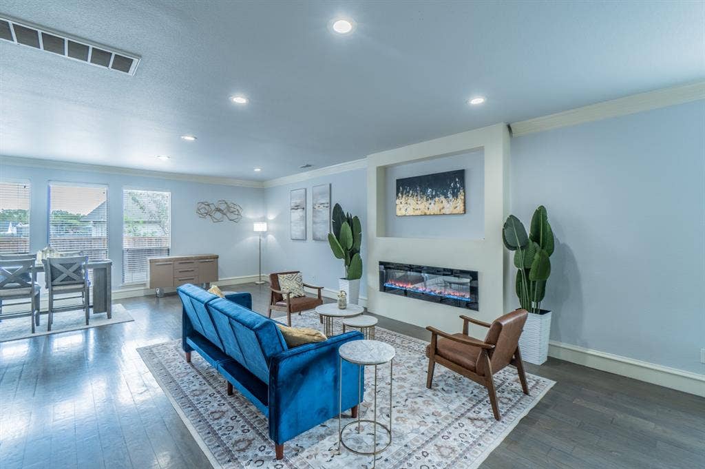 Living area featuring wood-finish flooring, recessed lighting, and a linear wall-mounted electric fireplace set into a recessed niche