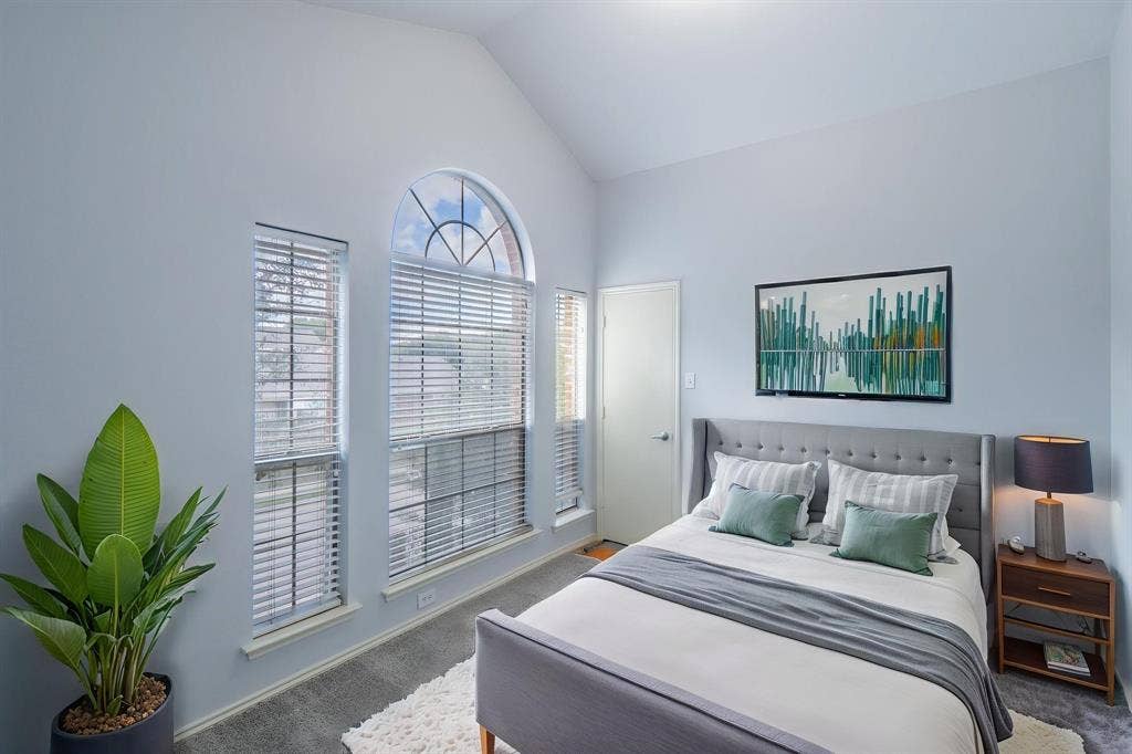 Vaulted ceiling, arched window with multi-pane detailing, and neutral wall tones