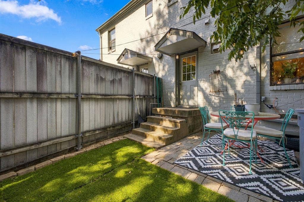 4904 Lahoma Street, #4904, Dallas, TX 75235 Fenced backyard featuring a paver patio, synthetic turf lawn, and a brick exterior with metal door awnings