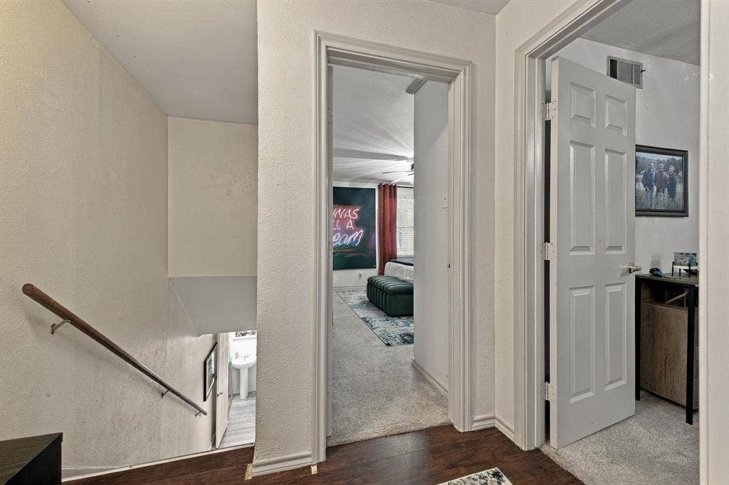 4904 Lahoma Street, #4904, Dallas, TX 75235 Interior hallway featuring wood-finish flooring, white paneled doors, and a staircase with a mounted metal handrail