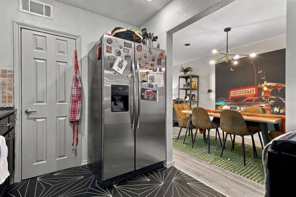 4904 Lahoma Street, #4904, Dallas, TX 75235 Stainless steel side-by-side refrigerator, geometric patterned floor tile, six-panel interior door with satin nickel hardware, and multi-arm chandelier lighting