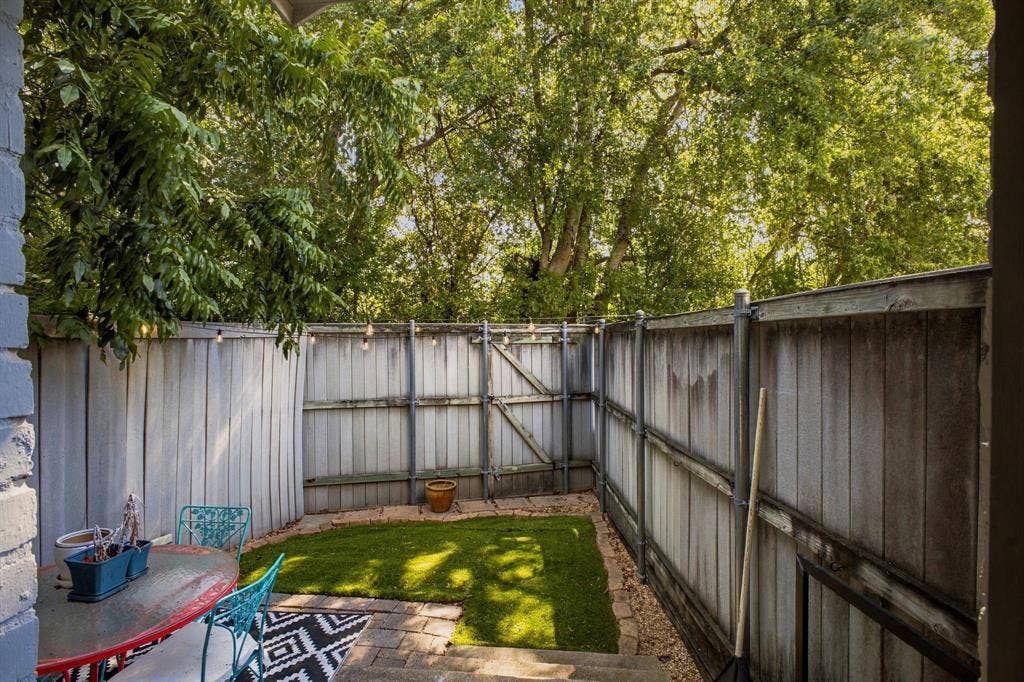 4904 Lahoma Street, #4904, Dallas, TX 75235 Enclosed outdoor space featuring a wood-panel fence, synthetic grass lawn, paver patio, and mature trees