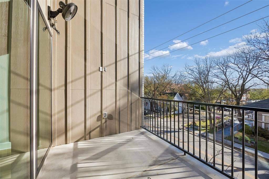 Covered balcony featuring vertical board siding, concrete flooring, and a black metal railing