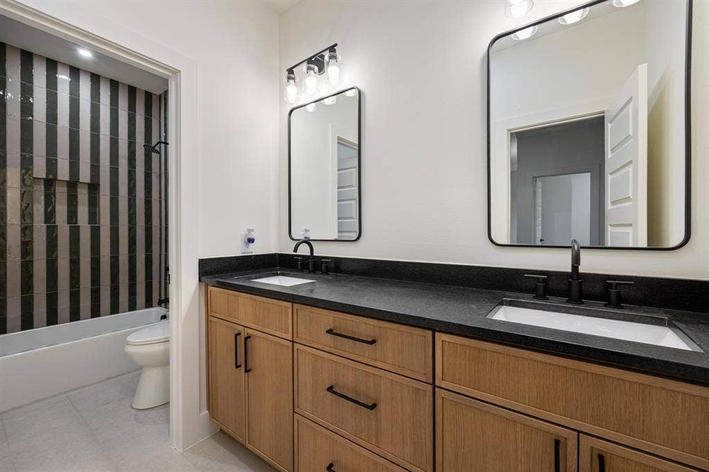 2719 Andrea Lane, Dallas, TX 75228 Guest bath with striped shower tile and dual vanity.