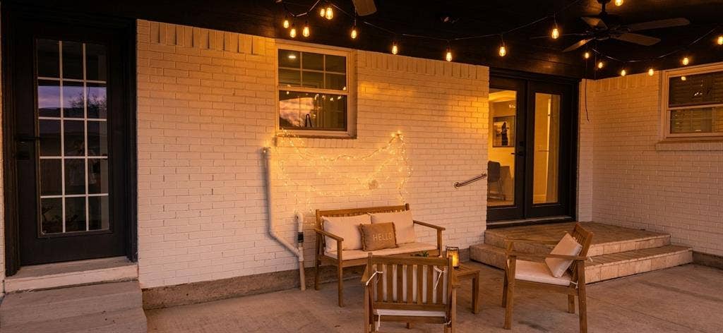 513 Vernet Street, Richardson, TX 75080 Covered patio featuring white brick exterior walls, dual glass-paned entry doors, a multi-pane single entry door, and stone-surfaced steps