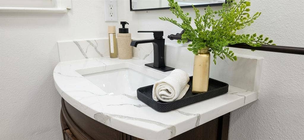 513 Vernet Street, Richardson, TX 75080 Curved vanity featuring a white surface with grey veining, integrated basin, matte black faucet, and framed mirror