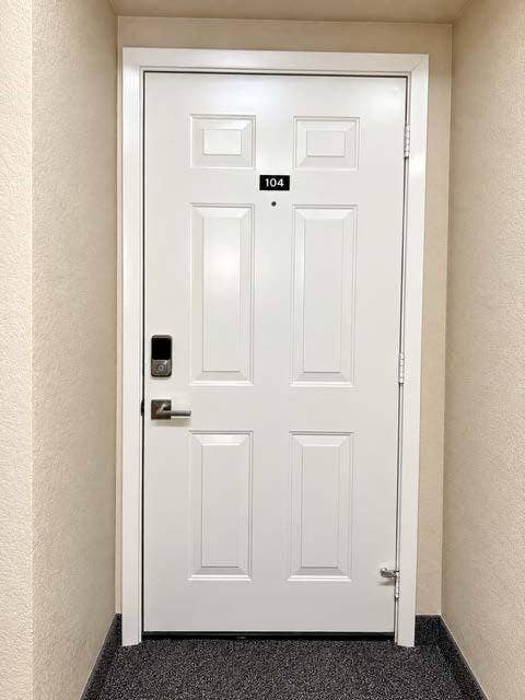 11450 Audelia Road, #104, Dallas, TX 75243 White six-panel door featuring a brushed nickel lever handle, integrated electronic keypad, and door-mounted peephole