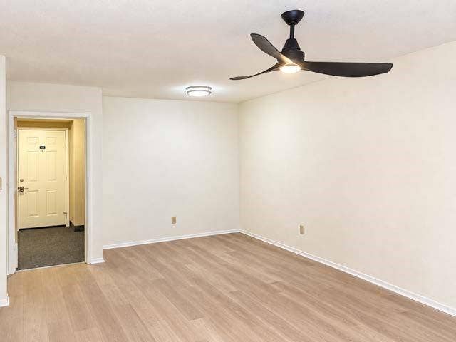 11450 Audelia Road, #104, Dallas, TX 75243 Interior room featuring wood-finish flooring, a matte black three-blade ceiling fan with integrated lighting, and a flush-mount ceiling light fixture