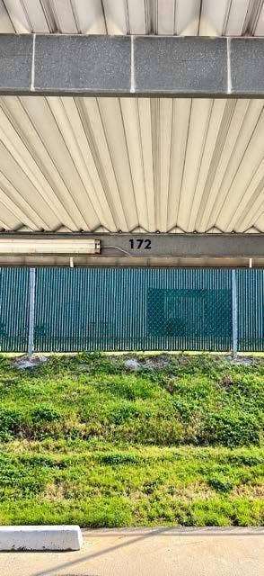 11450 Audelia Road, #104, Dallas, TX 75243 Covered parking #172 space featuring a corrugated metal roof, integrated overhead lighting, and numbered stall identification