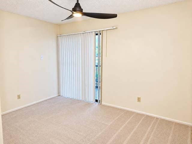 11450 Audelia Road, #104, Dallas, TX 75243 Room featuring neutral carpeting, a ceiling fan with integrated lighting, and sliding glass doors with vertical blinds