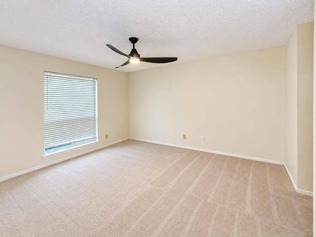 11450 Audelia Road, #104, Dallas, TX 75243 Neutral wall coloring, wall-to-wall carpeting, window with fitted horizontal blinds, and a three-blade matte black ceiling fan with an integrated light fixture