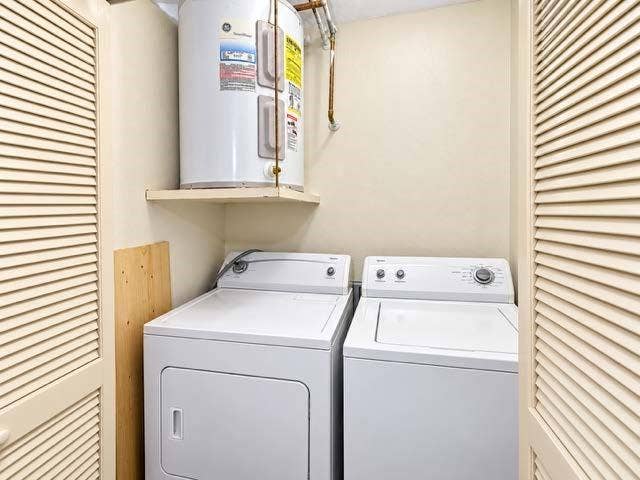 11450 Audelia Road, #104, Dallas, TX 75243 Laundry area featuring dual louvered closet doors and a wall-mounted shelving unit with an electric water heater