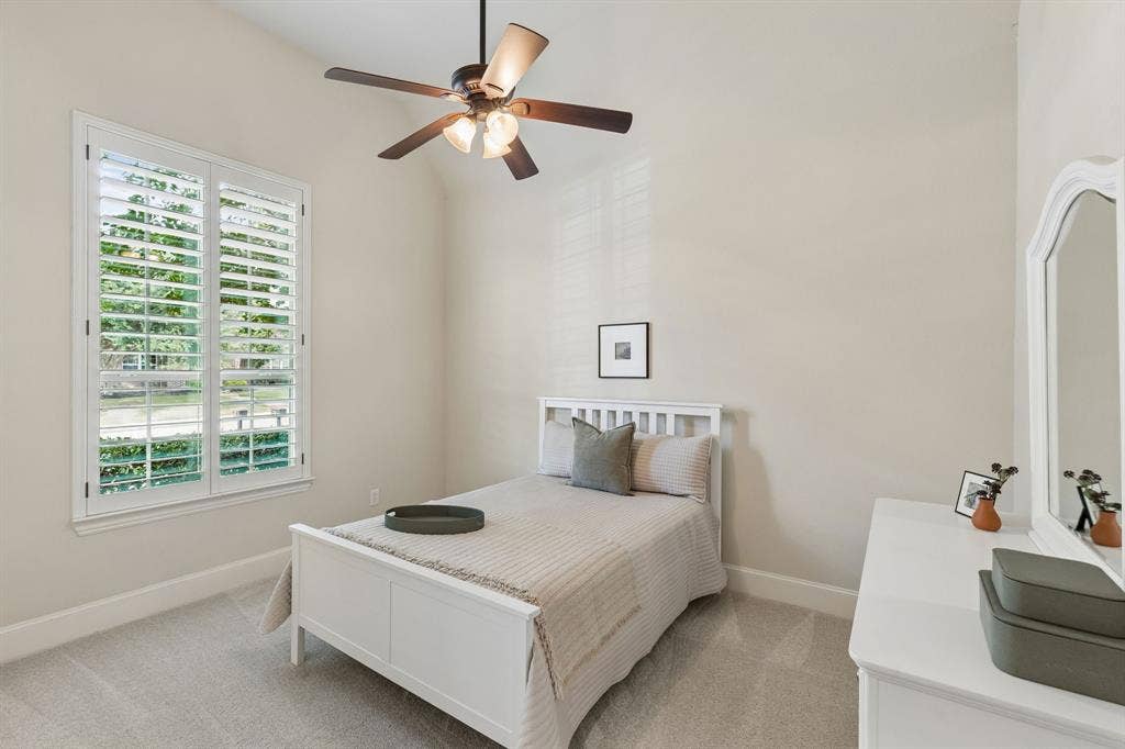 Vaulted ceilings, carpeted flooring, and plantation shutters featuring adjustable louvers, complemented by a multi-blade ceiling fan with integrated lighting