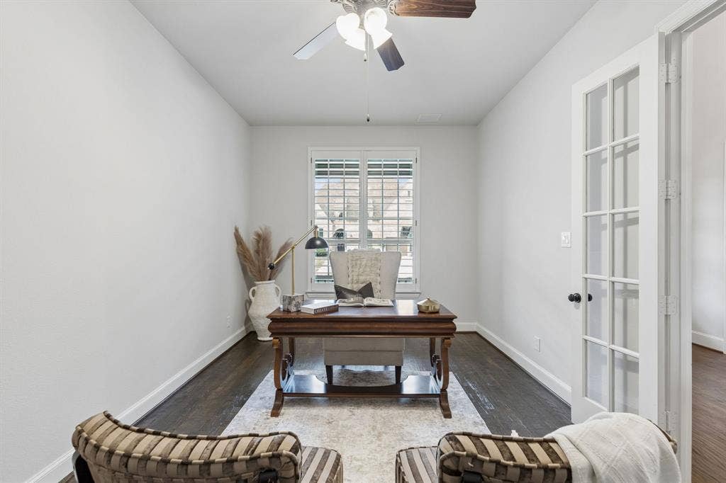 Wood-finish flooring, white French doors with glass panes, plantation shutters, and a ceiling fan with light fixture