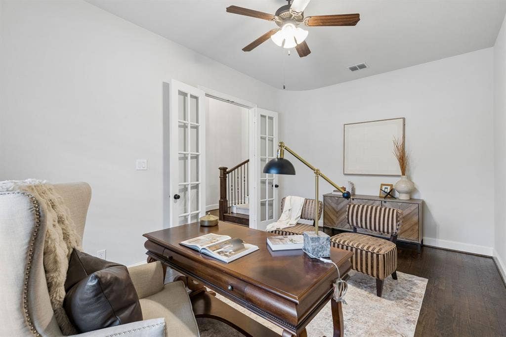 Room featuring dark wood-finish flooring, white French doors, and a ceiling fan with integrated light fixture