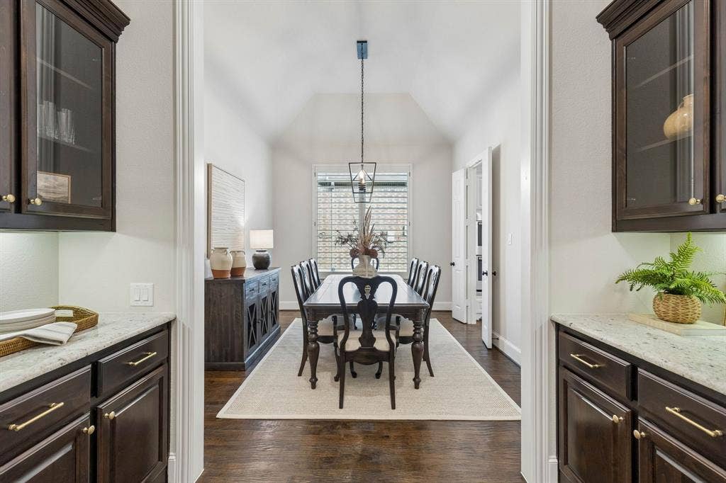 Butler's pantry featuring dark wood cabinetry, stone countertops, and glass-front upper storage