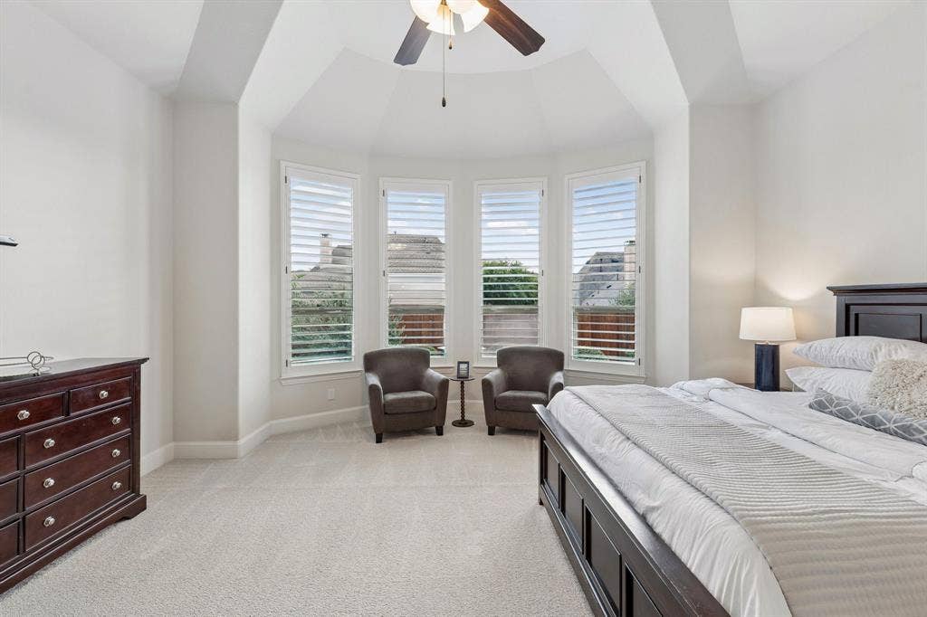 Tray ceiling, bay window with plantation shutters, and ceiling fan