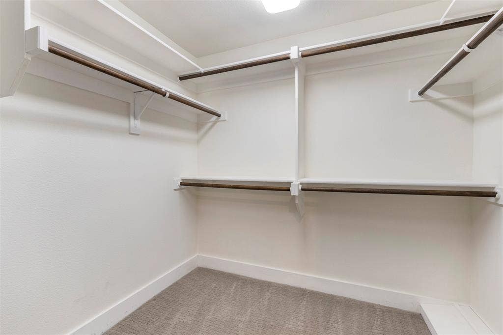 901 Oak Street, McKinney, TX 75069 Walk-in closet featuring tiered white shelving, wood-finish garment rods, and wall-to-wall carpeting
