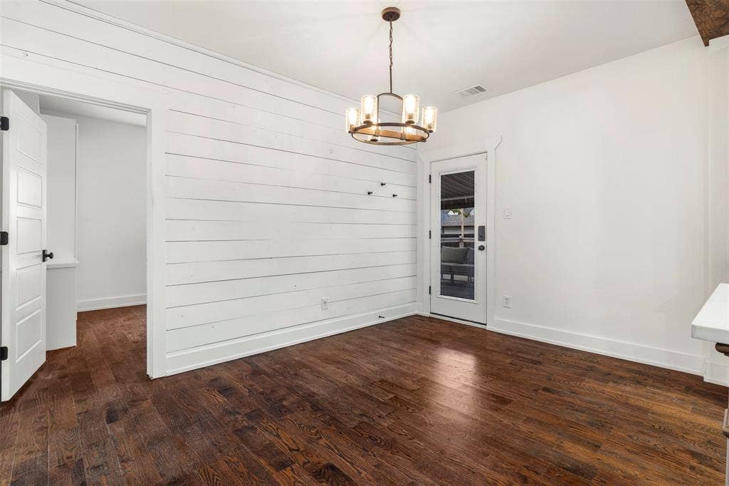 901 Oak Street, McKinney, TX 75069 Room featuring wood-finish flooring, white horizontal plank wall detailing, a multi-light circular chandelier, and a single-lite glass panel door