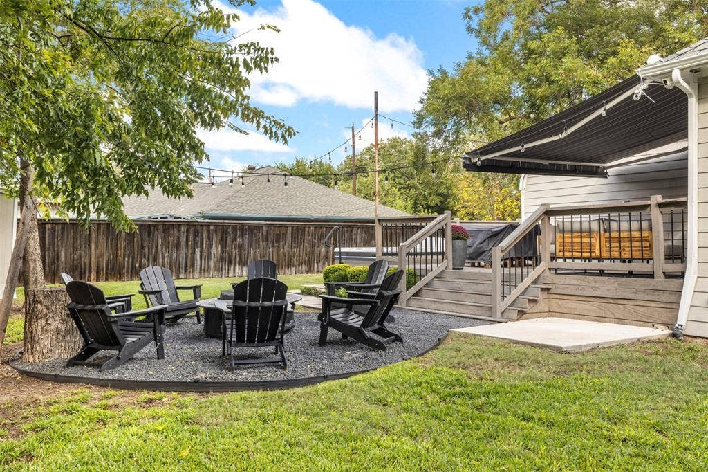 901 Oak Street, McKinney, TX 75069 Backyard featuring a tiered composite deck, retractable awning, gravel fire pit area, and wood privacy fencing