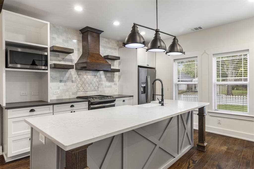 901 Oak Street, McKinney, TX 75069 Kitchen featuring a central island with a quartz countertop, custom wood-finish range hood, tile backsplash, built-in cabinetry, and wood-finish flooring