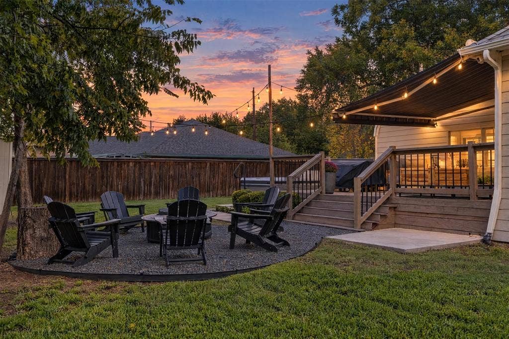901 Oak Street, McKinney, TX 75069 Backyard featuring an elevated wood deck with a retractable awning, a gravel fire pit area, and a wood privacy fence