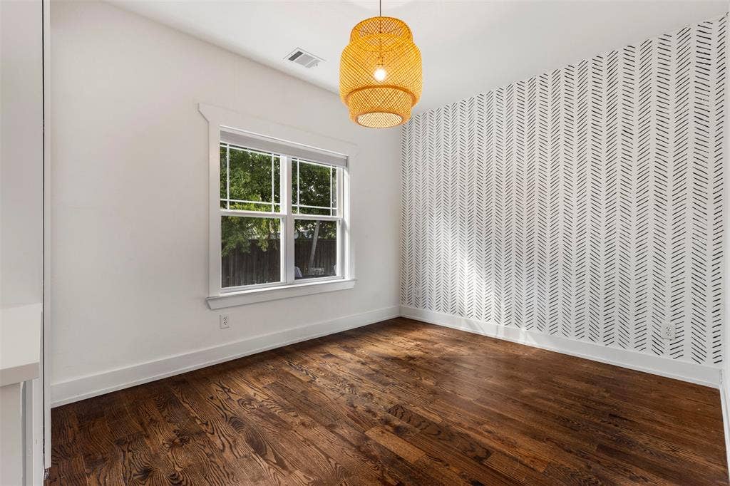901 Oak Street, McKinney, TX 75069 Interior space featuring wood-finish flooring, a herringbone-patterned accent wall, a multi-pane window with detailed trim, and a woven pendant light fixture