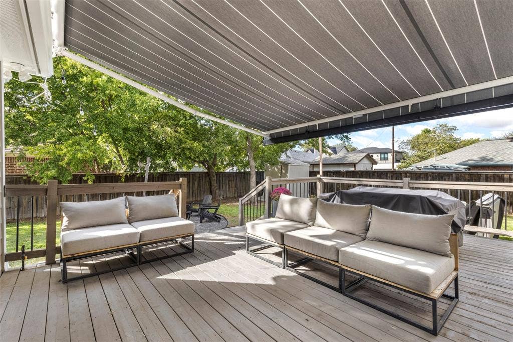 901 Oak Street, McKinney, TX 75069 Elevated wooden deck featuring a retractable fabric awning, perimeter wood railing, and a fenced backyard