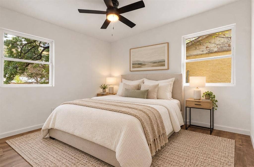 4813 Alandale Drive, Forest Hill, TX 76119 Neutral-toned room featuring wood-finish flooring, dual windows, and a matte black ceiling fan with integrated lighting virtually staged