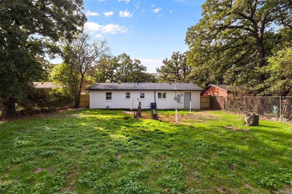 4813 Alandale Drive, Forest Hill, TX 76119 Expansive backyard featuring mature trees, a white painted brick exterior, and wood privacy fencing