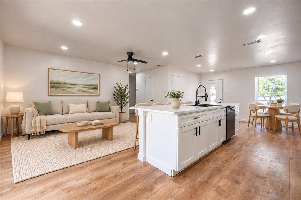Open-concept interior featuring wood-finish flooring, recessed lighting, and a central island with a contrasting faucet