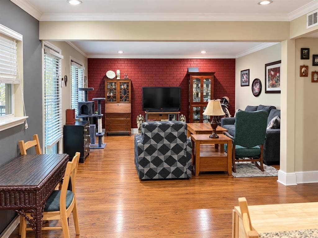 7730 Meadow Park Drive, #222, Dallas, TX 75230 Interior featuring wood-finish flooring, a red painted brick accent wall, and recessed ceiling lighting