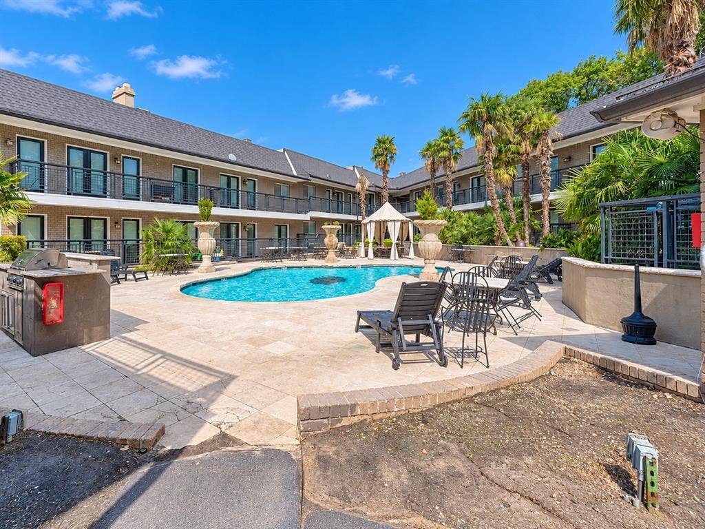 7730 Meadow Park Drive, #222, Dallas, TX 75230 Courtyard swimming pool featuring stone-style hardscaping, built-in outdoor kitchen, pergola, and elevated balcony railings