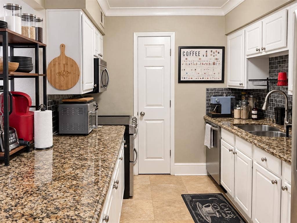 7730 Meadow Park Drive, #222, Dallas, TX 75230 Kitchen featuring white cabinetry, stone-finish countertops, subway tile backsplash, stainless steel sink with gooseneck faucet, and tile flooring
